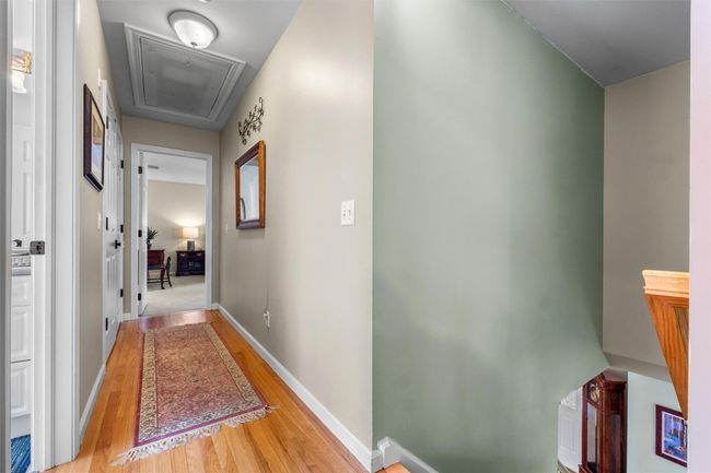 Corridor featuring pull down attic access, laundry and hardwood floors. | Image 20