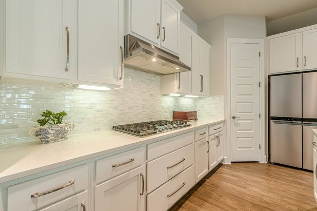 Kitchen with appliances with stainless steel finishes, under cabinet range hood, white cabinets, light countertops, and tasteful backsplash | Image 12