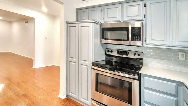 Kitchen with appliances with stainless steel finishes, gray cabinets, decorative backsplash, and light wood-type flooring | Image 17