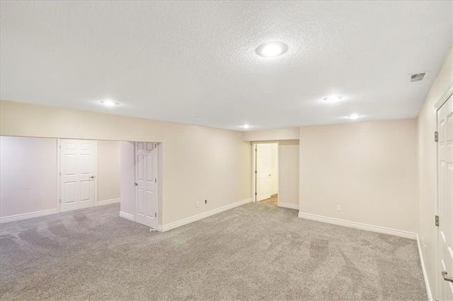 Finished below grade area with a textured ceiling, visible vents, baseboards, carpet flooring, and recessed lighting | Image 35