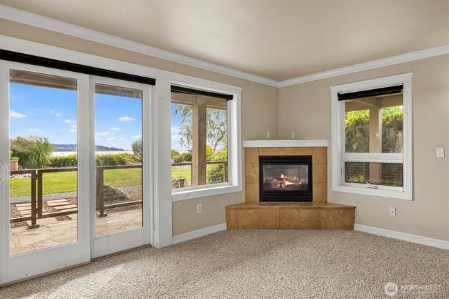 Living room with cozy gas fireplace, door to outdoor living and new carpet. | Image 5