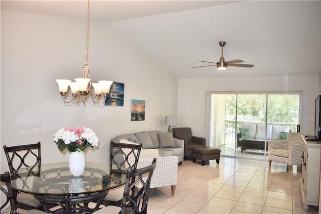 Living room with light tile, ceiling fan with notable chandelier, and high vaulted ceiling | Image 5
