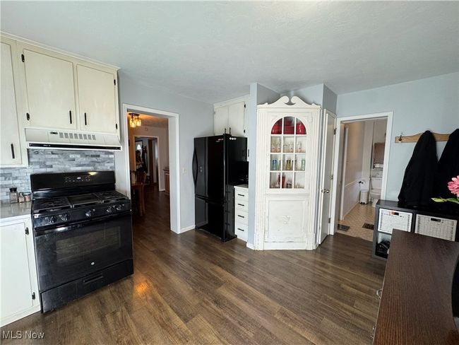 Kitchen featuring black appliances, light countertops, decorative backsplash, dark wood-style floors, and exhaust hood | Image 16