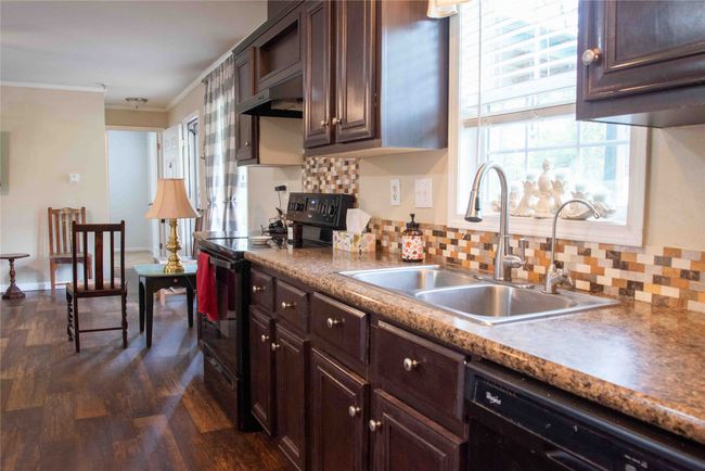 Kitchen featuring a sink, backsplash, black appliances, and under cabinet range hood | Image 22