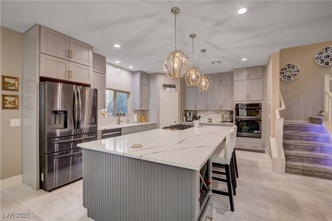 Kitchen with gray cabinets, a center island, decorative backsplash, and appliances with stainless steel finishes | Image 21