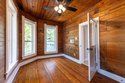 Spare room featuring ceiling fan, wooden walls, wood ceiling, and wood-type flooring | Image 3