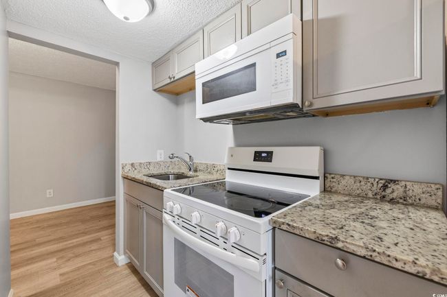Kitchen featuring white appliances, a sink, gray cabinetry, light wood-style floors, and a textured ceiling | Image 9