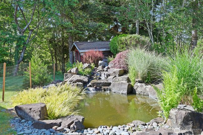 Soothing pond with waterfall feature. Fire pit is just behind the pond in the rockery. | Image 37