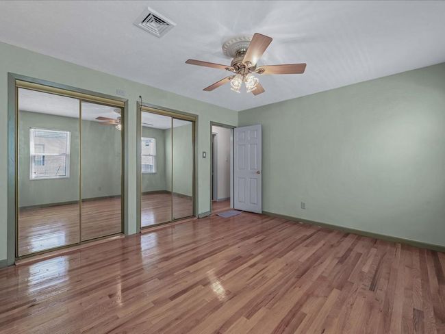 Unfurnished bedroom featuring multiple closets, light wood-style flooring, and a ceiling fan | Image 13