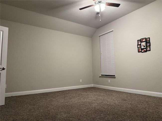 Spare room featuring vaulted ceiling, ceiling fan, and dark carpet | Image 8