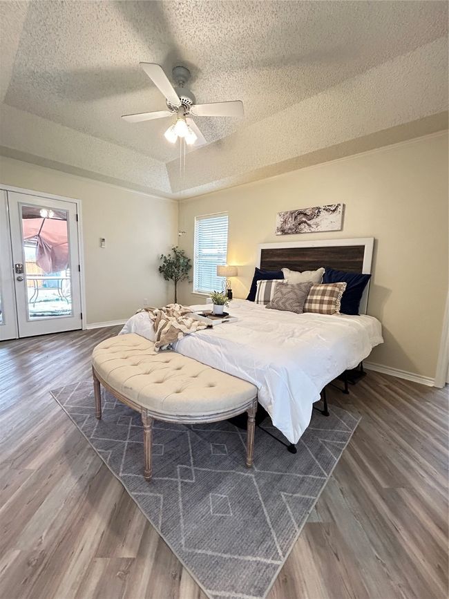 Bedroom with multiple windows, a raised ceiling, wood finished floors, and access to outside | Image 33