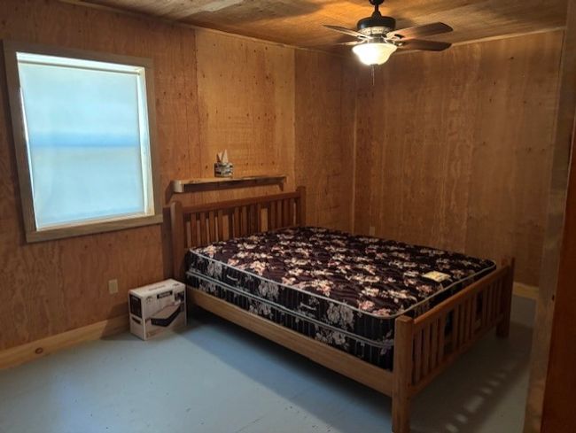 Bedroom featuring wooden walls, wood ceiling, and ceiling fan | Image 16