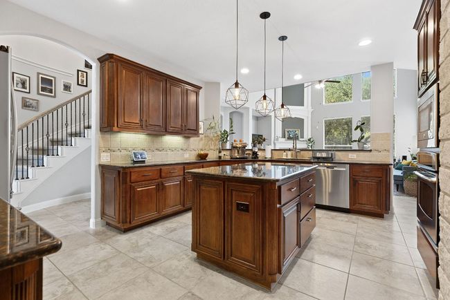 Ample cabinet and countertop space illuminated by pendant and recessed lighting. | Image 12
