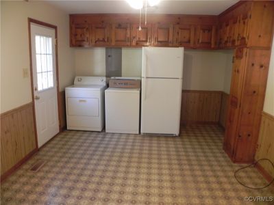 Clothes washing area with wood walls, separate washer and dryer, and ceiling fan | Image 3