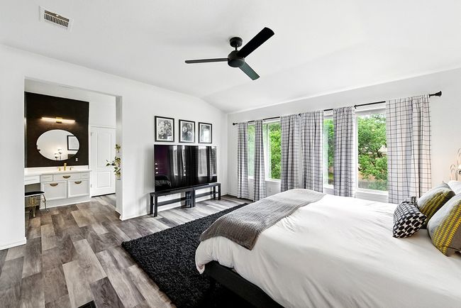Bedroom with visible vents, wood finished floors, lofted ceiling, and a tile fireplace | Image 18
