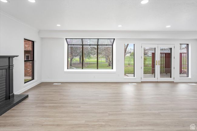 Unfurnished living room featuring a fireplace with raised hearth, baseboards, light wood finished floors, and recessed lighting | Image 5