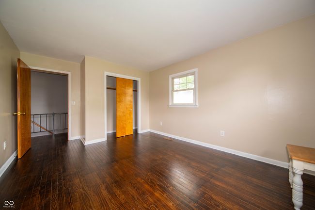 unfurnished bedroom with baseboards, dark wood-type flooring, and a closet | Image 36