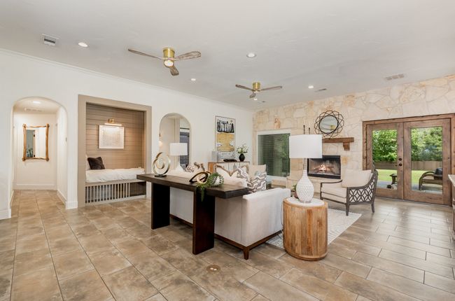 Living room featuring a ceiling fan, crown molding, arched walkways, recessed lighting, and a fireplace | Image 7