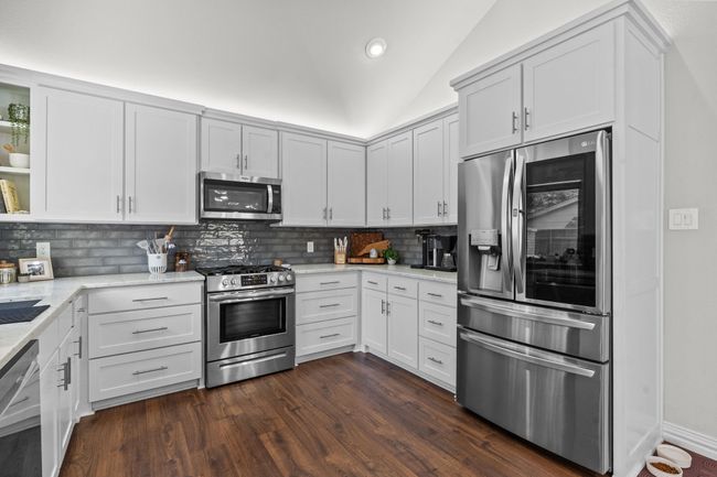 Kitchen with stainless steel appliances, decorative backsplash, light stone countertops, vaulted ceiling | Image 5