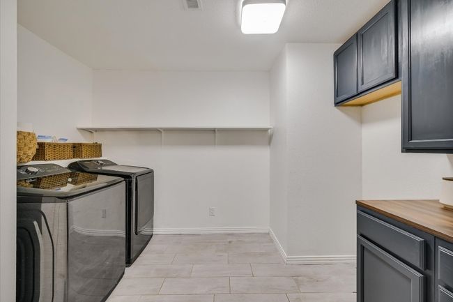 Spacious laundry area with added storage and counter space. | Image 5