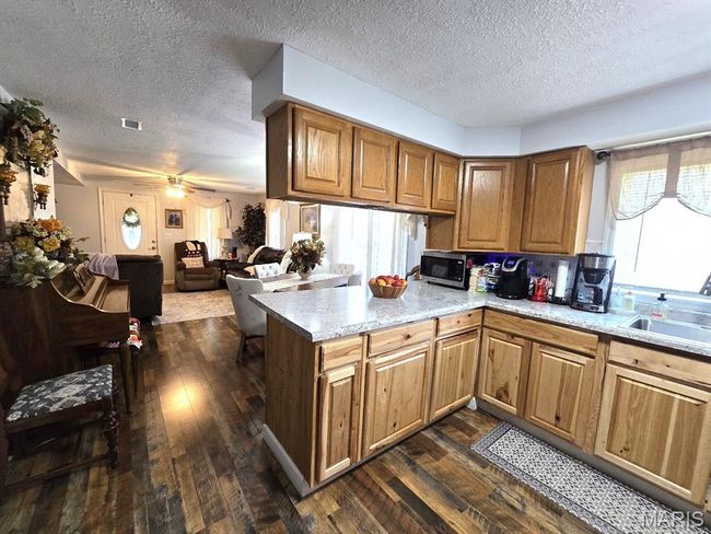 Kitchen featuring stainless steel microwave, a textured ceiling, dark wood finished floors, a peninsula, and plenty of natural light | Image 8