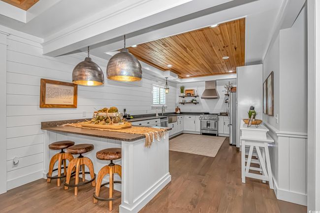 Kitchen with wooden ceiling, a peninsula, appliances with stainless steel finishes, dark wood-style floors, and ventilation hood | Image 7