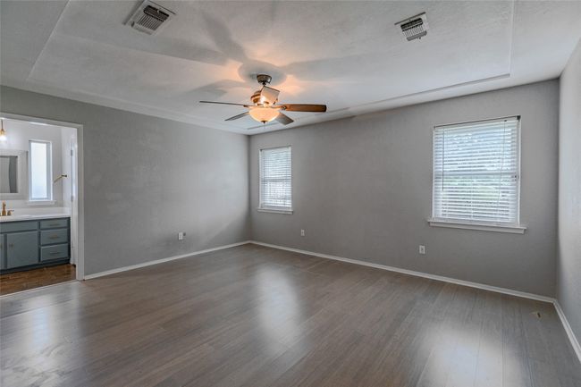 Unfurnished bedroom with dark wood-type flooring, ceiling fan, and connected bathroom | Image 27
