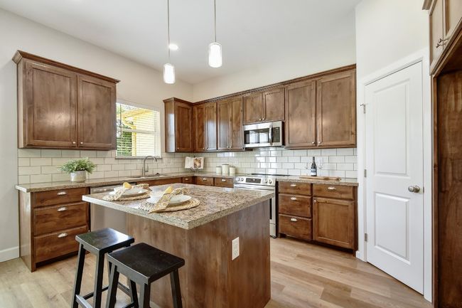 Kitchen with stainless steel appliances, light wood-type flooring, a kitchen bar, and backsplash | Image 8