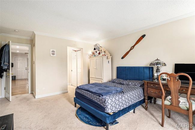 Bedroom with light colored carpet, ornamental molding, a textured ceiling, and a closet | Image 11