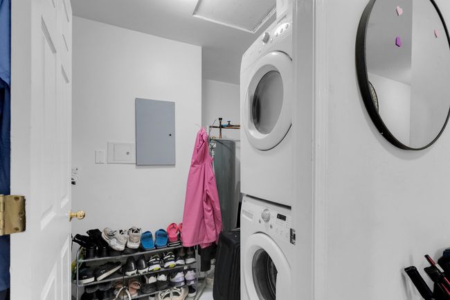 Laundry area featuring stacked washing machine and dryer and electric panel | Image 13