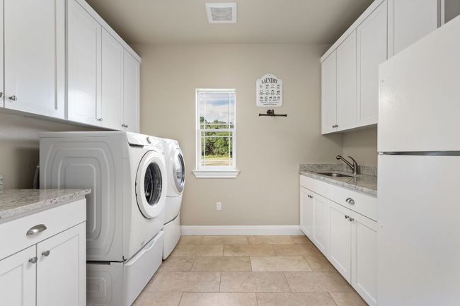 The spacious laundry room offers ample counter space, storage, and convenience, making household chores a breeze. | Image 25