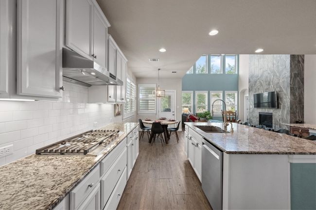 Entertainer's Dream Kitchen with stainless steel appliances, under cabinet range hood, a large fireplace, recessed lighting, and dark wood-type flooring | Image 13