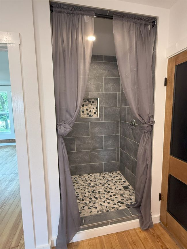 Bathroom featuring a tile shower and wood finished floors | Image 23