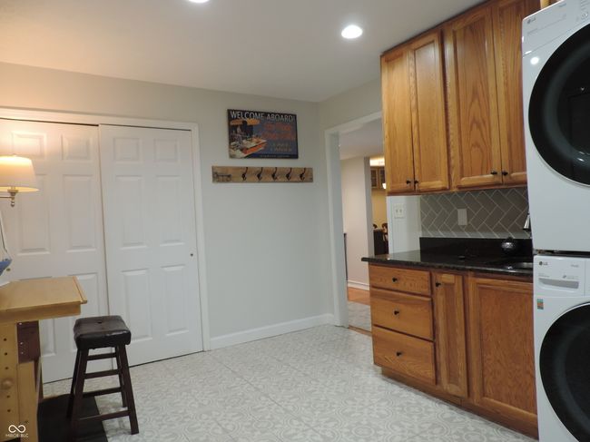 kitchen with tasteful backsplash, recessed lighting, brown cabinetry, and stacked washer / drying machine. | Image 26