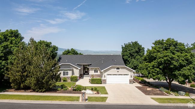 Single story home with an attached garage, stucco siding, stone siding, concrete driveway, and a mountain view | Image 41