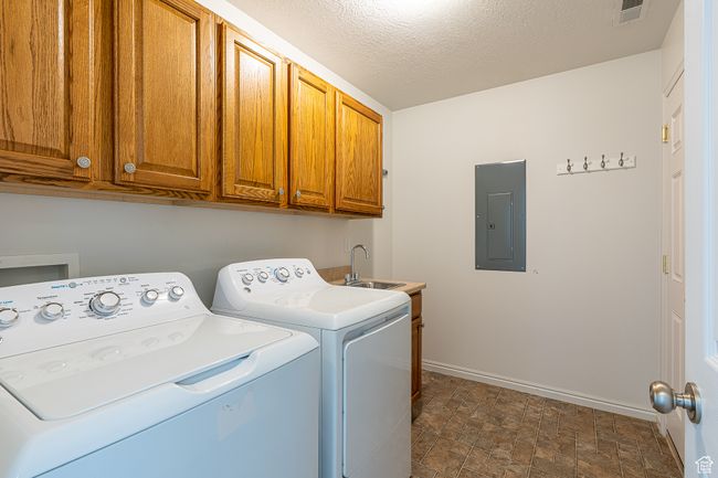 Laundry room with baseboards, visible vents, cabinet space, washing machine and dryer, and electric panel | Image 26