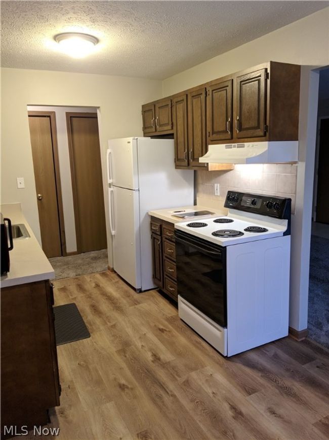 Kitchen featuring white appliances, sink, backsplash, and light wood-type flooring | Image 13