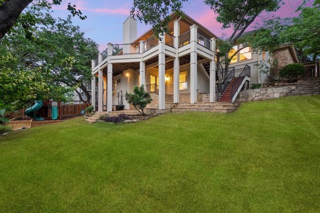 Back of house at dusk featuring a balcony, stairs, a chimney, and a playground | Image 27