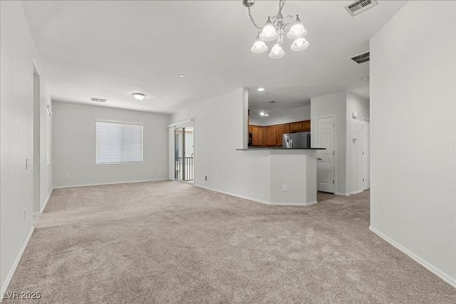 Unfurnished living room featuring light colored carpet and a chandelier | Image 5