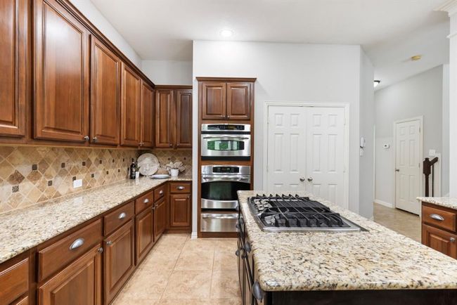 Stainless appliances with "in island" gas range. Hall on right leads to a full bath, secondary bedroom, utility room and door to 2 car garage. | Image 18