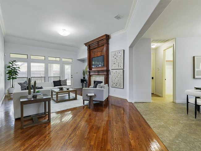 Living room with a large fireplace, ornamental molding, and wood finished floors | Image 15