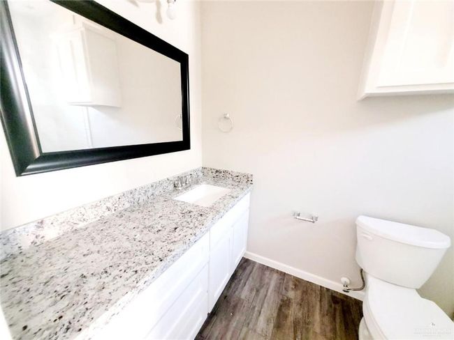 Bathroom featuring baseboards, wood finished floors, toilet, and vanity | Image 5