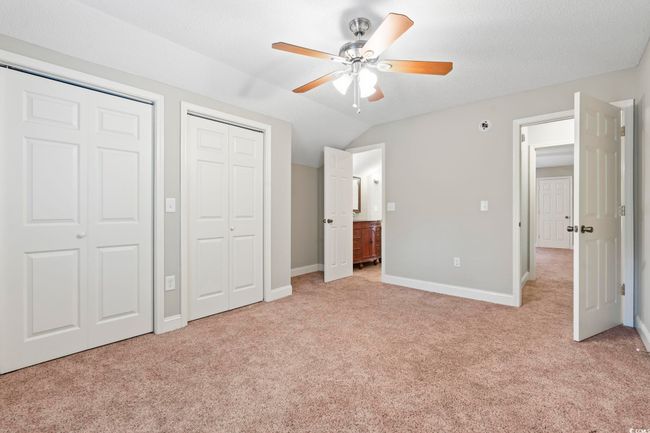Unfurnished bedroom featuring two closets, light colored carpet, vaulted ceiling, baseboards, and connected bathroom | Image 31