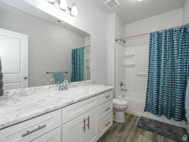 Full bathroom featuring visible vents, shower / bath combination with curtain, vanity, and wood finished floors | Image 28