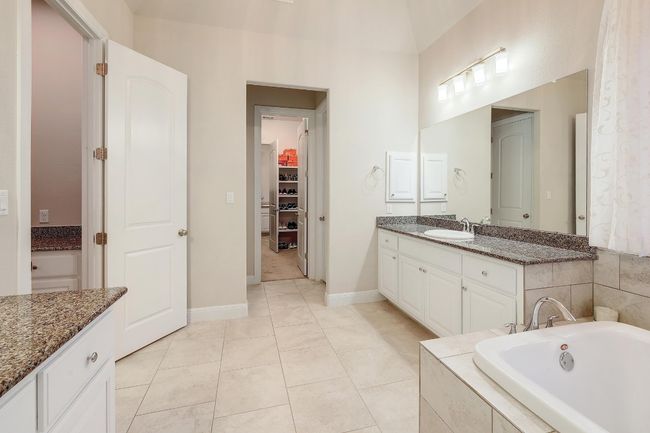 Bathroom featuring vanity, tile patterned flooring, a garden tub, and a spacious closet | Image 20