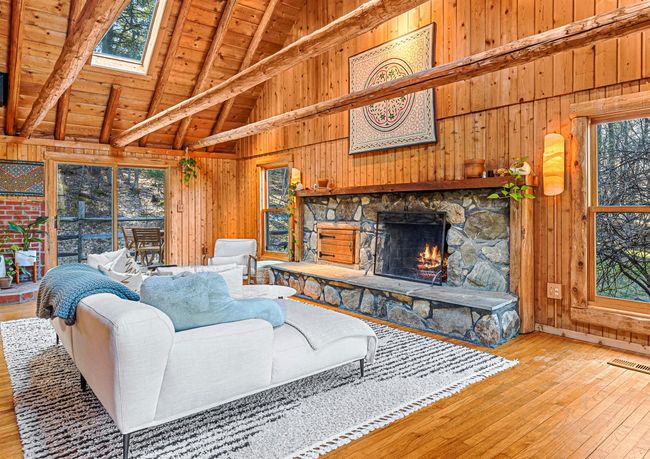Living room featuring wooden walls, light wood-style flooring, a skylight, and wood ceiling | Image 13