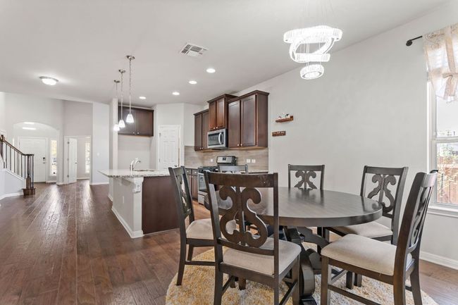 Dining space featuring dark wood-style floors, baseboards, visible vents, arched walkways, and recessed lighting | Image 16