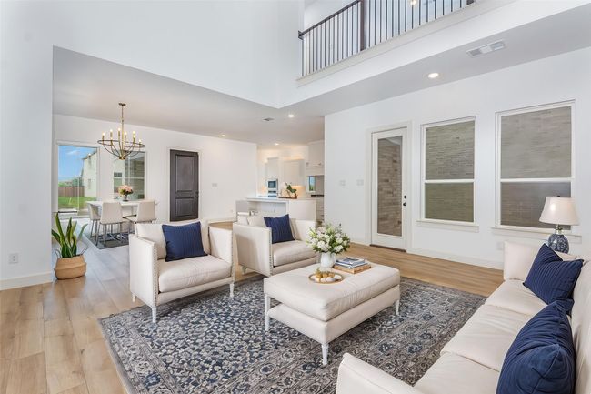 Living area with a chandelier, light wood-style floors, and a high ceiling | Image 12