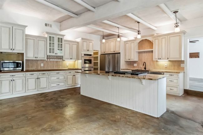 Kitchen with appliances with stainless steel finishes, finished concrete floors, tasteful backsplash, and beamed ceiling | Image 8