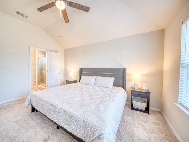 Bedroom featuring ceiling fan, lofted ceiling, light carpet, and ensuite bath | Image 9